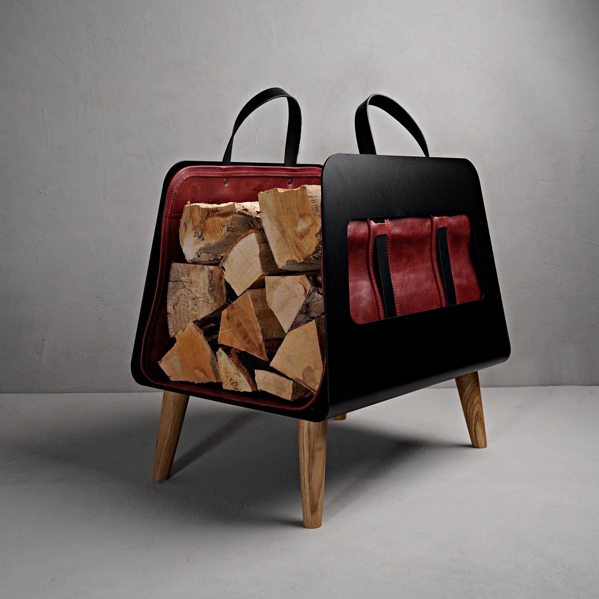 Brennholzkorb gefüllt mit Kaminholz in Ledertasche aus rotem Leder
