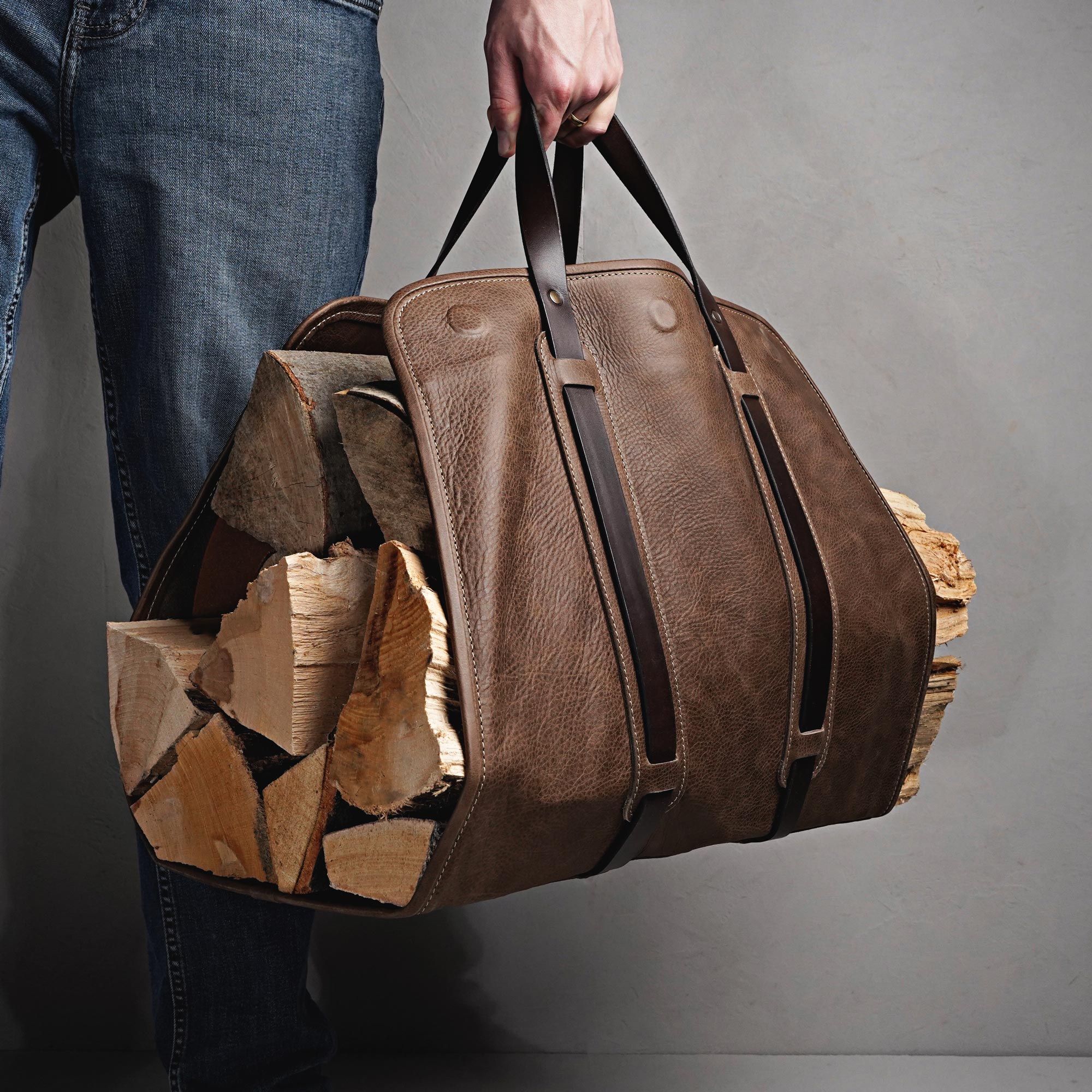 Mann trägt Kaminholztasche aus Leder mit Brennholz